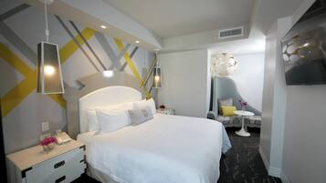 Une chambre d’hôtel moderne avec un grand lit, des tables de chevet, un bureau et une télévision.