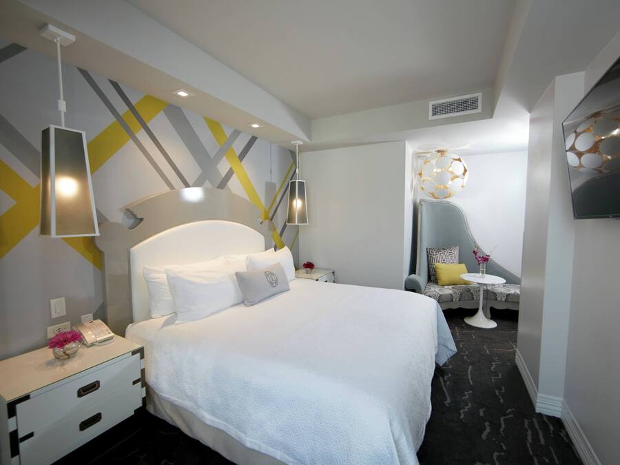 Une chambre d’hôtel moderne avec un grand lit, des tables de chevet, un bureau et une télévision.
