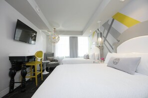Une chambre d’hôtel avec un lit, un bureau, une chaise, une télévision et une fenêtre avec des rideaux.