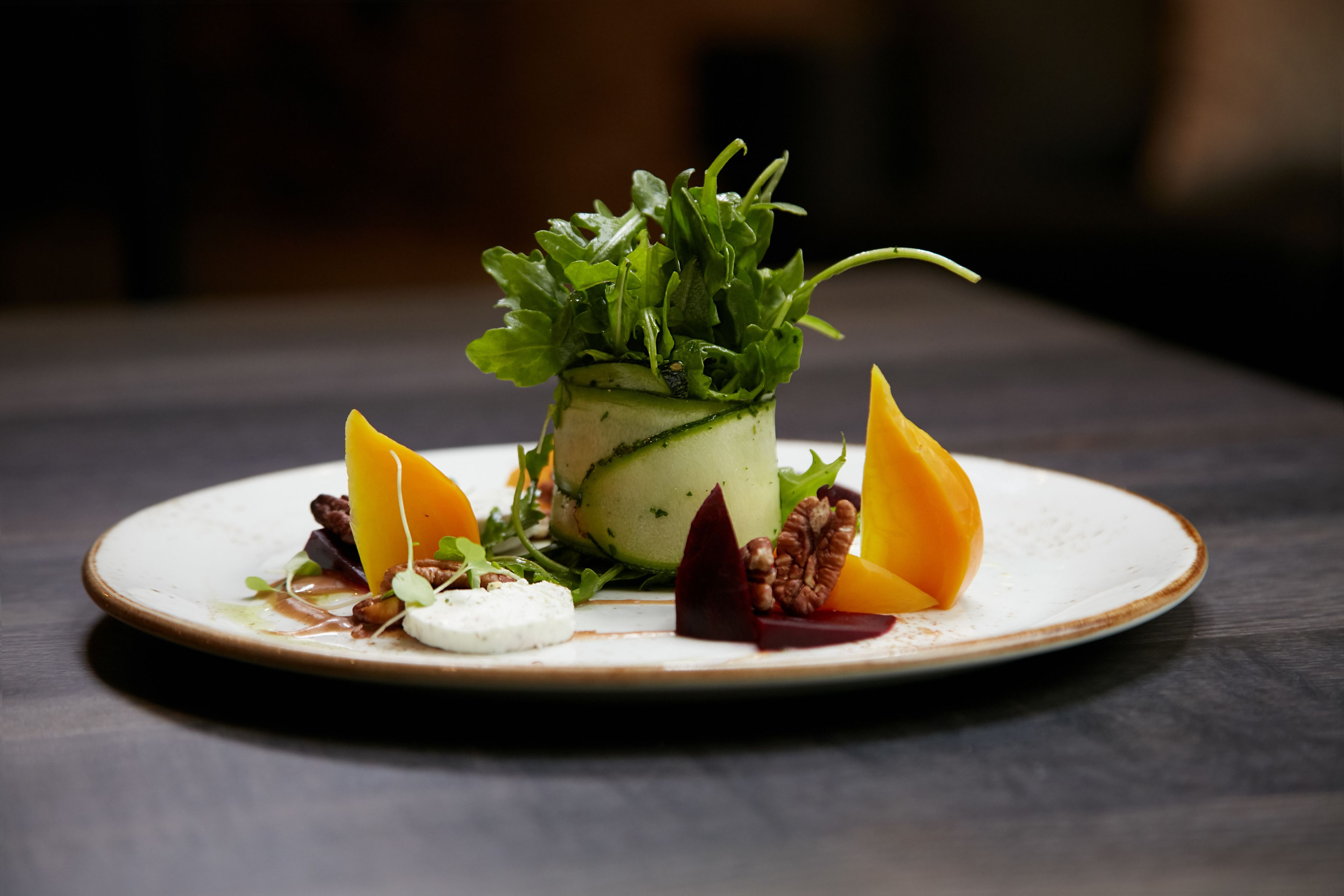Une assiette avec une salade de concombres, du fromage et des légumes.