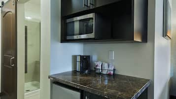 A compact kitchen with a built-in microwave, a coffee maker, and a small refrigerator.