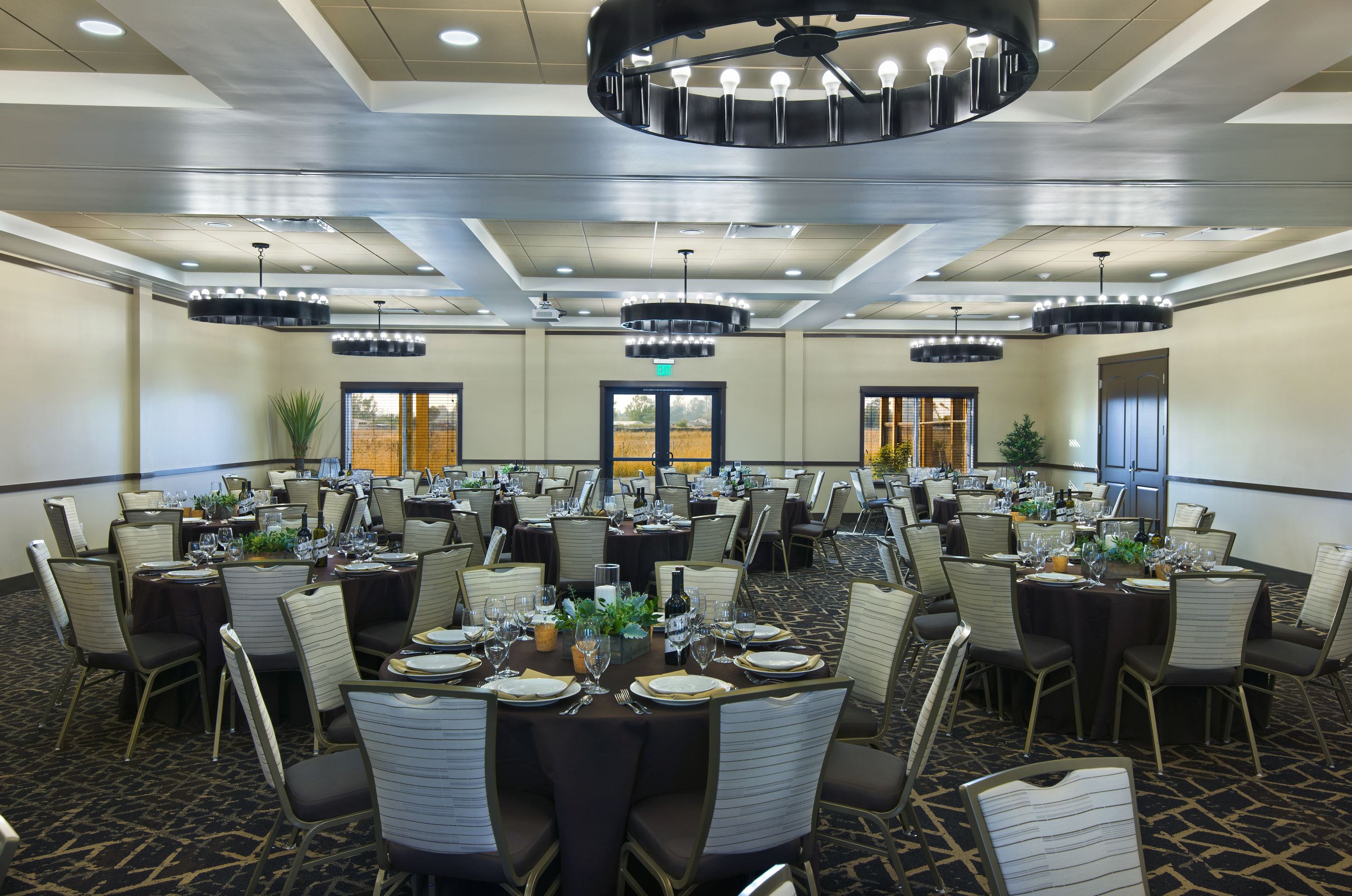 A banquet hall with multiple round tables set for dining, equipped with chairs, tables, and centerpieces.