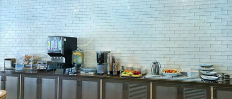 Un bar pour prendre le petit-déjeuner, équipé d’une machine à café, d’un panier de fruits et d’une variété d’aliments pour le petit-déjeuner.