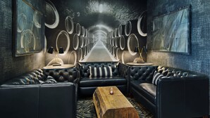 A modern lounge with leather sofas, a wooden coffee table, and a mural of barrels on the wall.