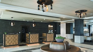 A modern lobby with a reception desk, seating area, and contemporary lighting fixtures.
