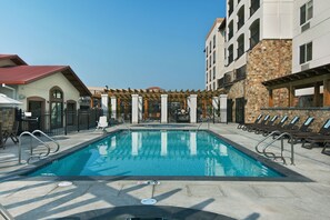 A swimming pool with lounge chairs and a covered seating area.