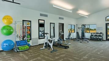 Un gimnasio con equipo de ejercicio, pelotas grandes de fitness y una fuente de agua.