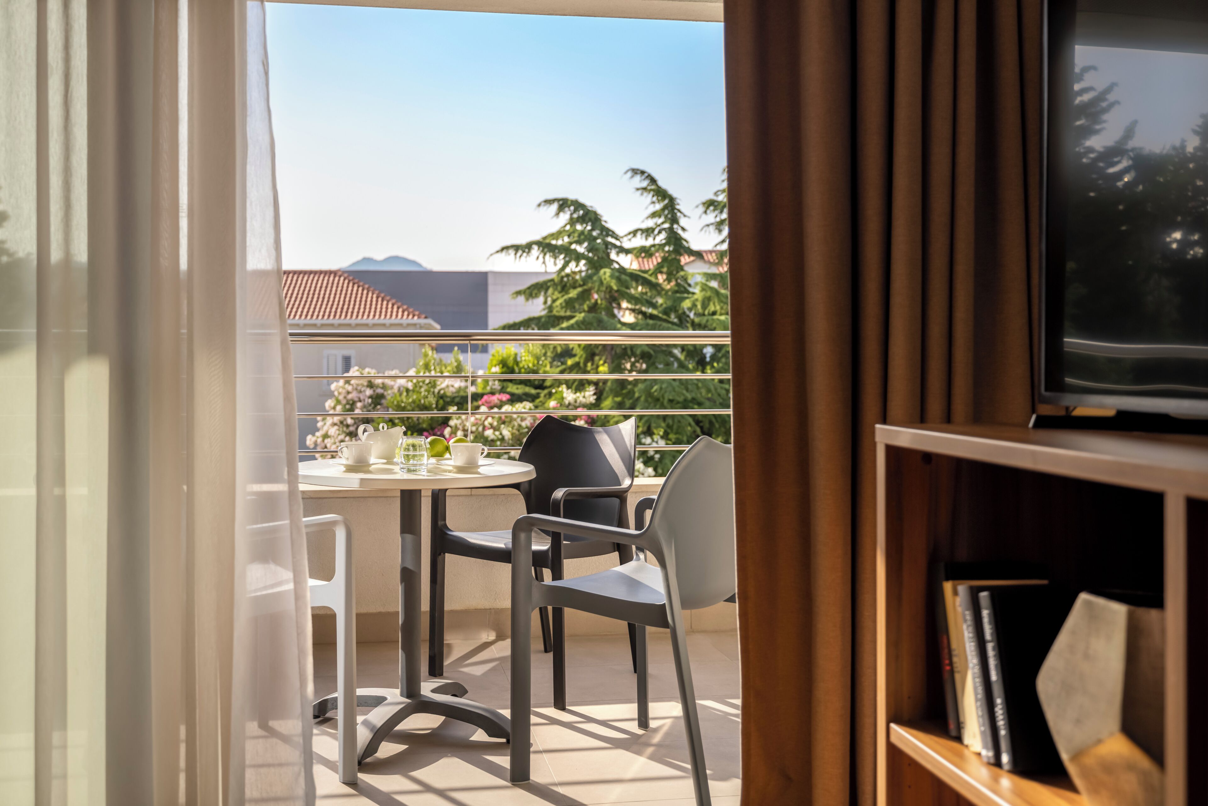 A balcony with a table, chairs, and a television.