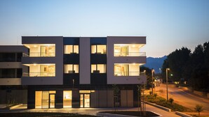 A modern multi-story hotel with illuminated balconies and a well-lit entrance.