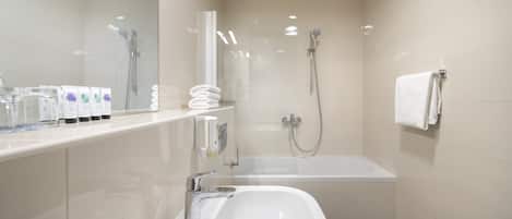 A modern bathroom with a bathtub, a shower, a sink, and a mirror.