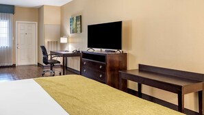 A hotel room with a bed, a desk, a chair, a television, and a dresser. - Best Western Plus Galveston Suites (Galveston)
