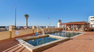 Relax by the pool surrounded by a palm tree and a covered seating area.