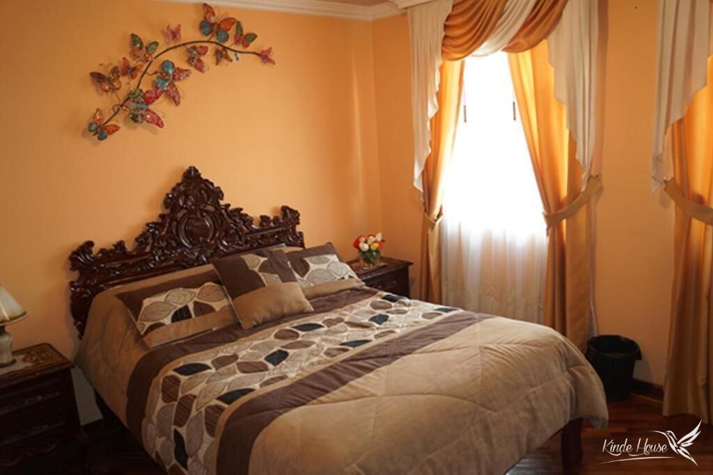 A bedroom with a large bed, ornate headboard, and a decorative wall piece.