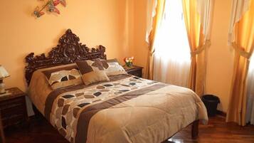 A bedroom with a large bed, wooden headboard, and a nightstand with a lamp.