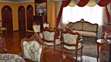 A traditional living room with ornate wooden furniture, a patterned rug, and a classic sofa.