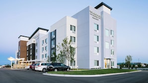 Ein modernes Hotel mit auffälliger Beschilderung, Parkplatz und gepflegter Grünfläche.
