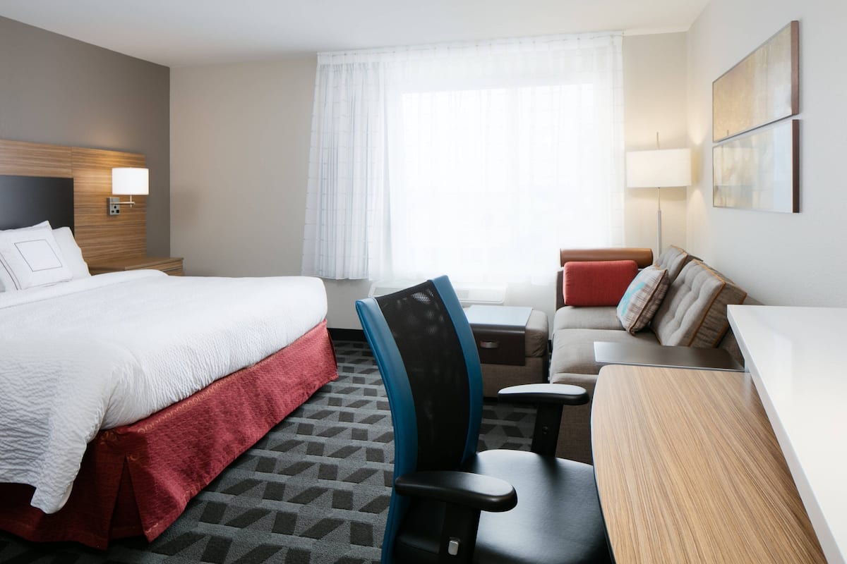 Une chambre d’hôtel avec un lit, un bureau, une chaise et un canapé.