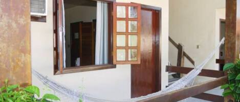 A room with a wooden door, a window with a view, and a hammock.