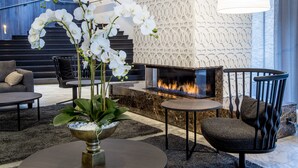 A modern living room with a fireplace, a sofa, a coffee table, and decorative plants. - Lydia Hotel (Tartu)