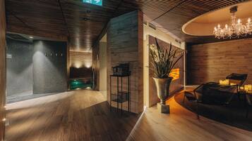 Un interior moderno con suelo de madera, una recepción, una araña y un letrero de salida verde.