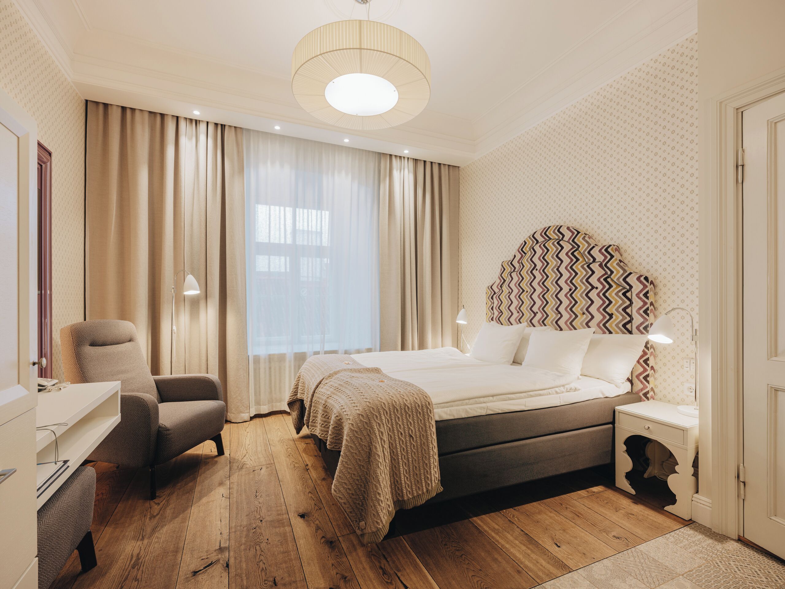 Een hotelkamer met een bed, een stoel, een bureau en een nachtkastje.