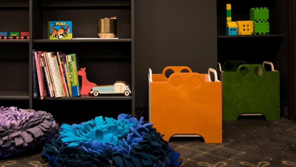 A room with a bookshelf, a toy car, and a colorful bean bag.