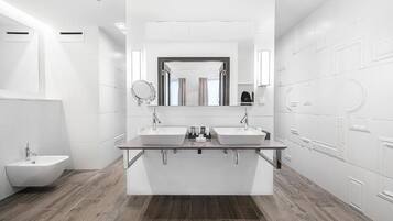 Un baño moderno con dos lavamanos, un mueble de tocador y un bidé.
