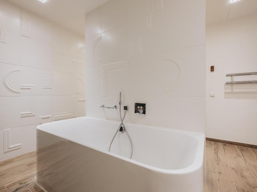 A modern bathroom with a freestanding bathtub, a towel rack, and a wall-mounted towel dispenser.
