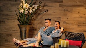 A couple relaxing on a wicker sofa with a potted orchid plant beside them. - Lydia Hotel (Tartu)