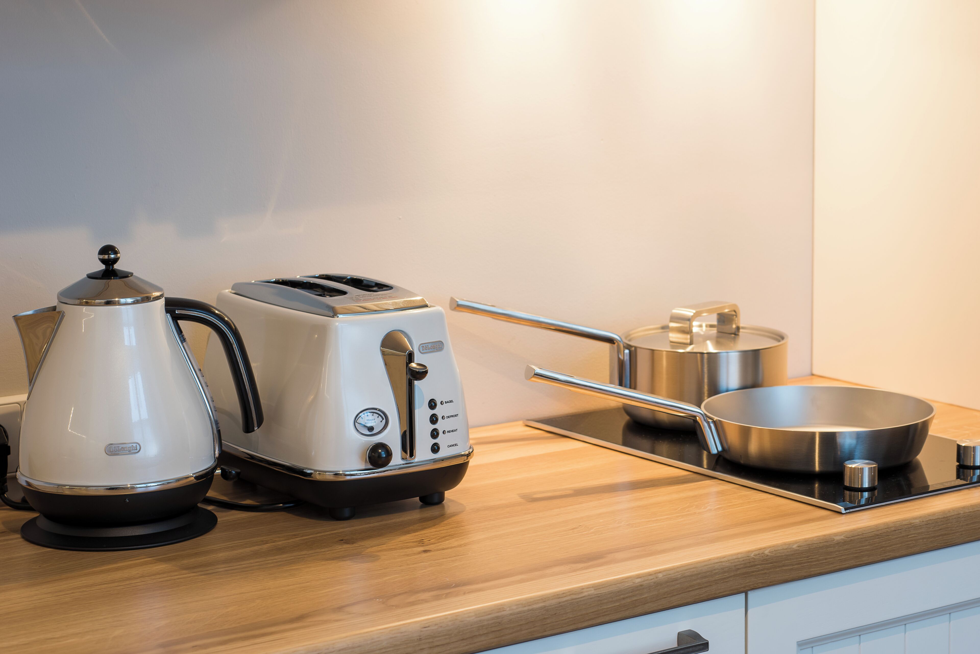 Una encimera de cocina con una tetera, un tostador y una sartén sobre una estufa.