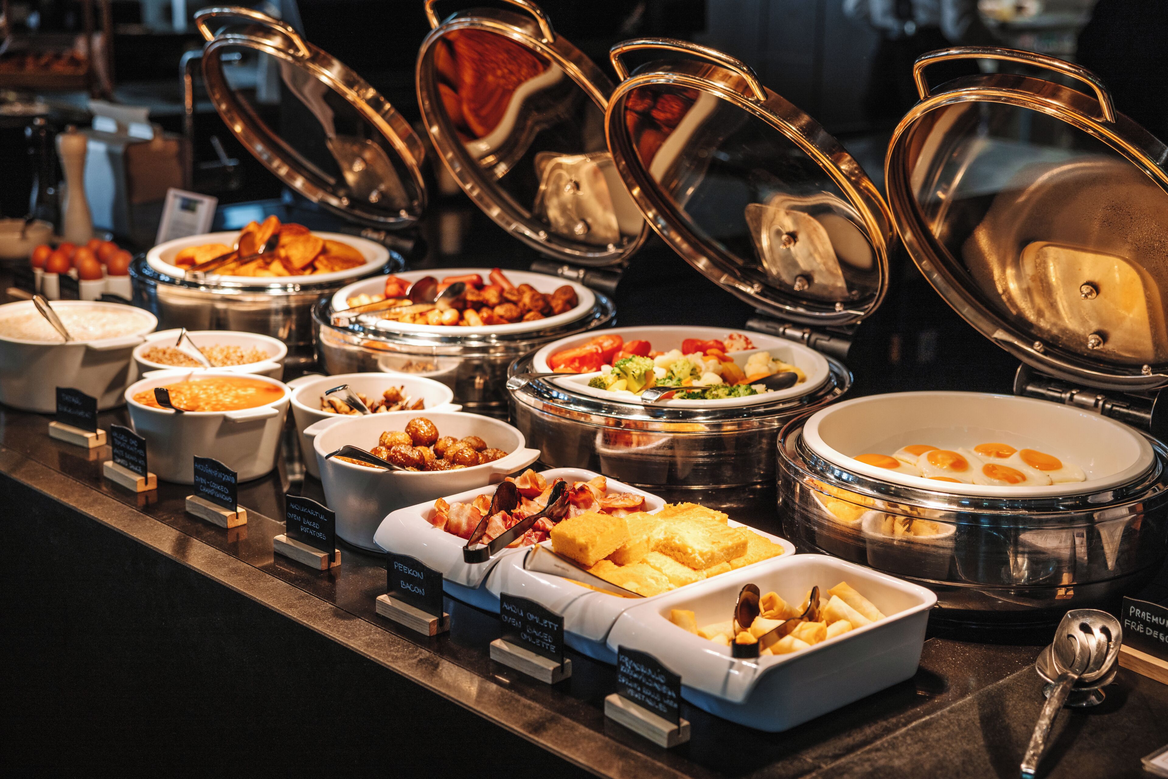 A buffet with various food options, including meats, vegetables, and baked goods.