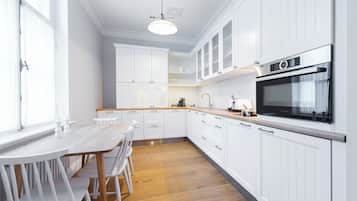 A modern kitchen with white cabinetry, a wooden dining table, and a Bosch oven.