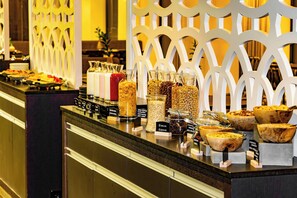 A buffet counter with various food items and containers labeled with names like "Raisin Raisin" and "Honey Almond." - Lydia Hotel (Tartu)