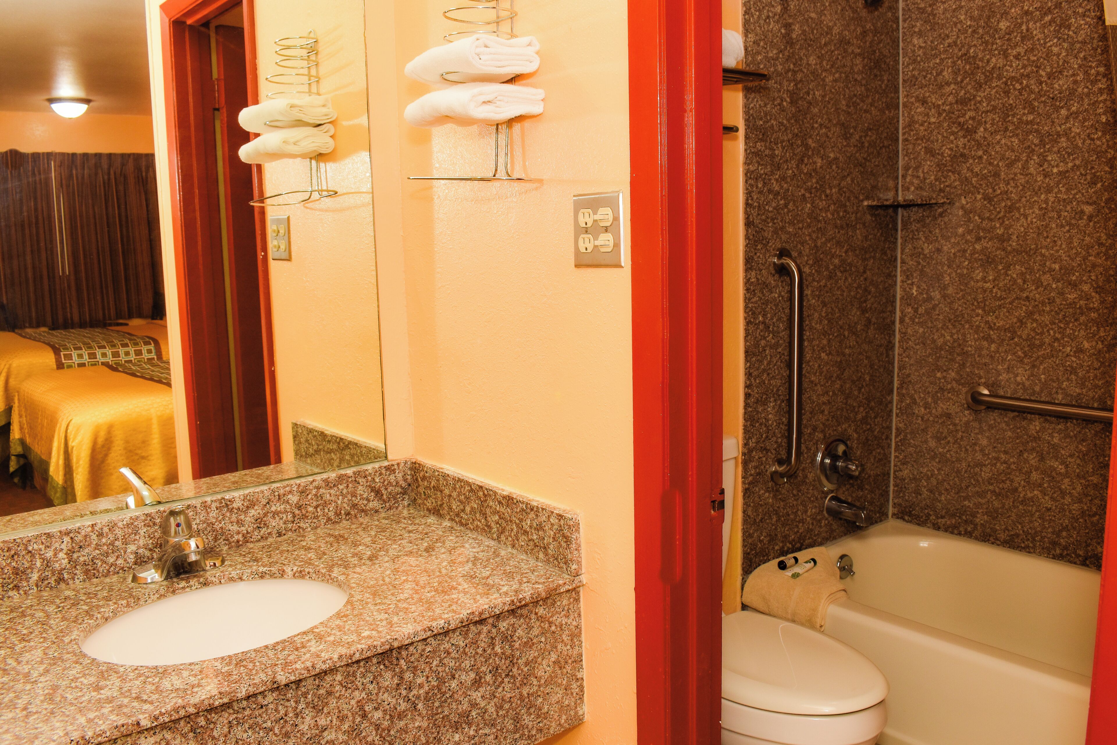 A bathroom with a granite countertop sink, a white toilet, and a bathtub.