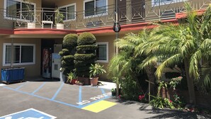 A multi-story building with a parking area marked "NO PARKING" and a Coca-Cola vending machine. - Fullerton Lodge (Fullerton)