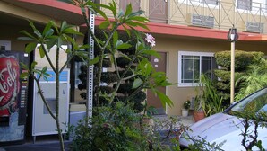 A multi-story building with balconies, a Coca-Cola vending machine, and various potted plants. - Fullerton Lodge (Fullerton)