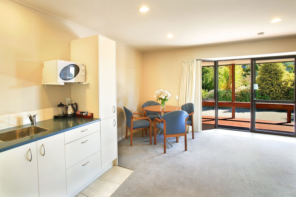 A modern kitchen with a built-in microwave, a sink, and a dining area with a table and chairs.