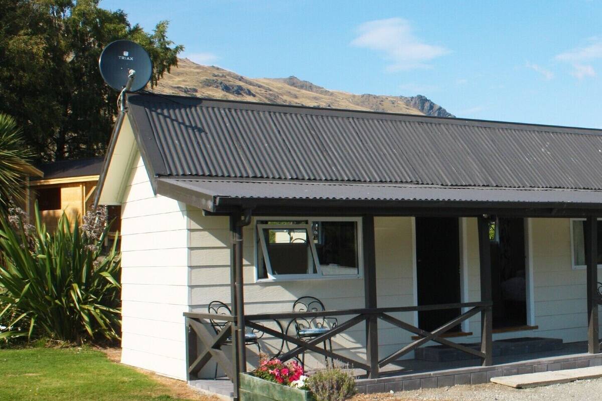 A single-story building with a corrugated metal roof, a satellite dish, and a covered porch with outdoor seating.