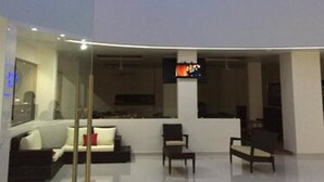 A modern interior with a glass partition, a sofa, a coffee table, and a flat-screen TV. - MH Grand Hotel (Ometepec)