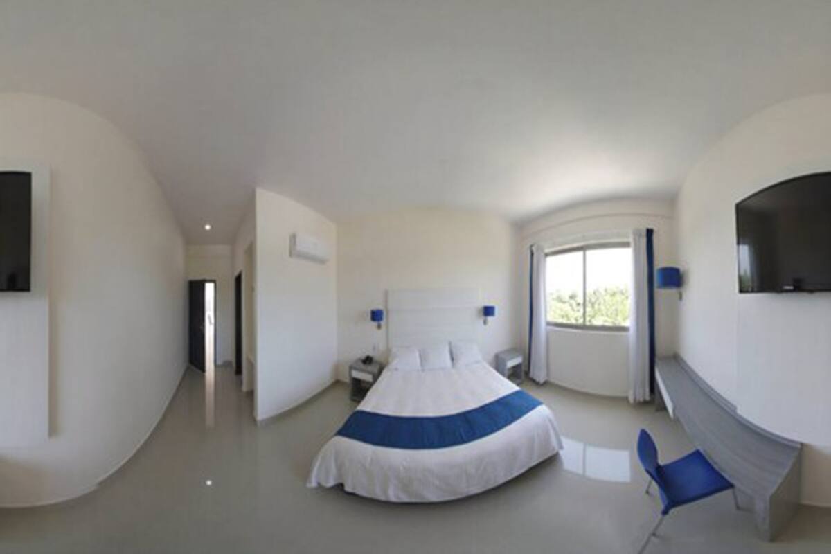 Una habitación de hotel moderna con una cama grande, mesitas de noche, un televisor de pantalla plana y una ventana con cortinas.