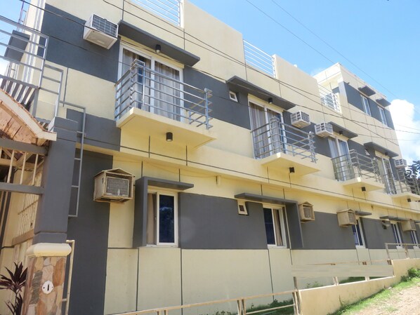 A multi-story residential building with balconies, air conditioning units, and a gated entrance.
