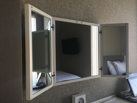 Una camera compatta con un letto, una scrivania piccola e una televisione.