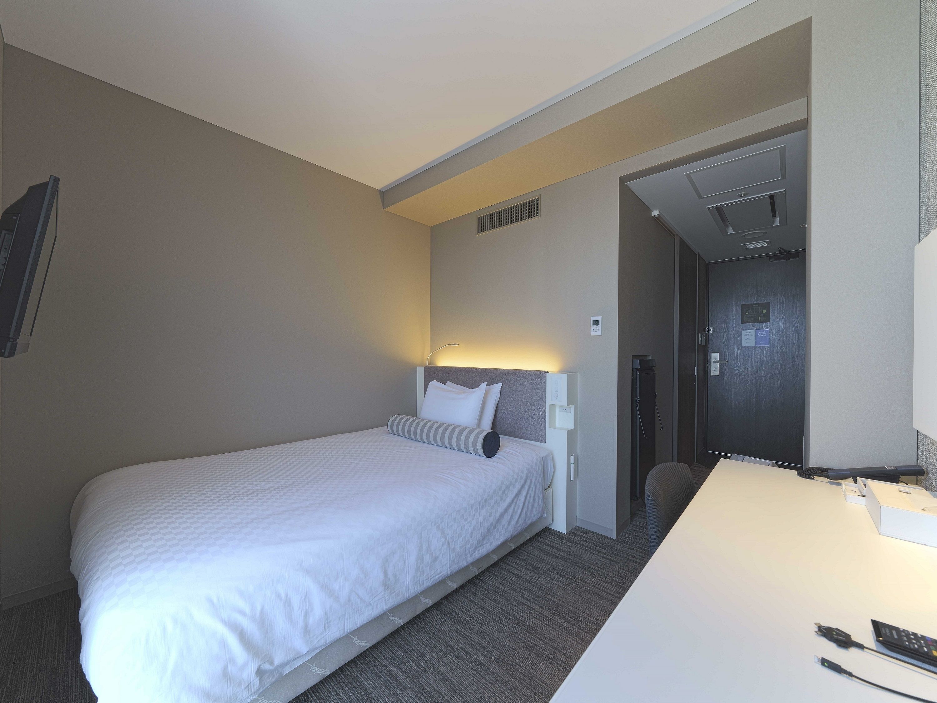 Habitación de hotel con cama, escritorio y zona de ducha.