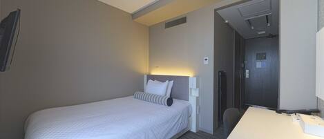 Habitación de hotel con cama, escritorio y zona de ducha.
