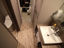 A modern bathroom with a wooden floor, a white sink, and a glass shower enclosure.