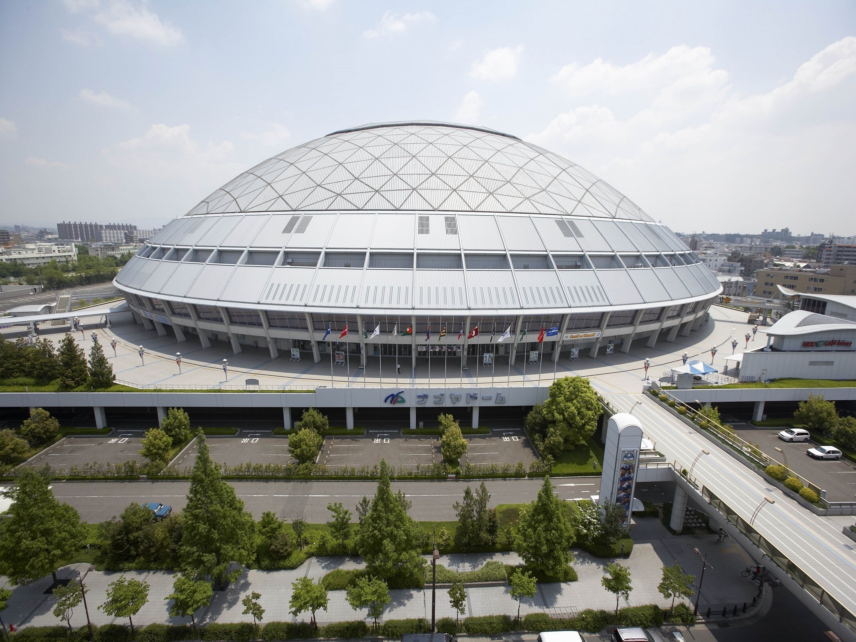 Un estadio grande y moderno con un techo abovedado distintivo y varias columnas de banderas.