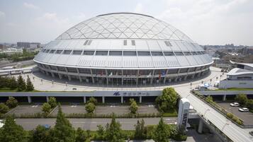 Un estadio grande y moderno con un techo abovedado distintivo y varias columnas de banderas.