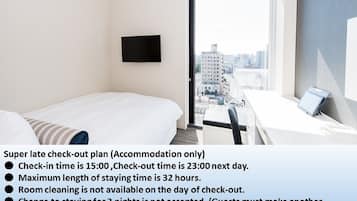 A hotel room with a bed, a desk, a chair, and a TV.