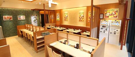 A restaurant with wooden booths, tiled walls, and ceiling lights.