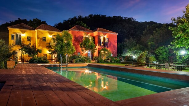 A two-story building with a swimming pool, surrounded by greenery and a wooden deck. - Davinci Di Khao Yai (Pak Chong)